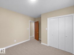 Neutral tone wall paint, light neutral carpeting, white trim, wood-finish interior door, and bi-fold closet doors - 