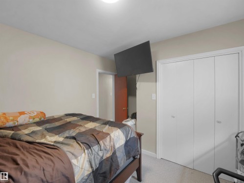 Neutral wall paint, light-colored carpeting, and bi-fold closet doors - 12002 48 Street Nw, Edmonton, AB 