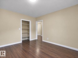 Wood-finish flooring, built-in shelving, neutral wall tones, and overhead lighting - 