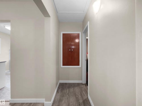 Wood-finish flooring with white trim, a built-in wall cabinet, and ceiling-mounted lighting - 12002 48 Street Nw, Edmonton, AB 