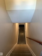 Carpeted staircase with a wood handrail and recessed lighting - 