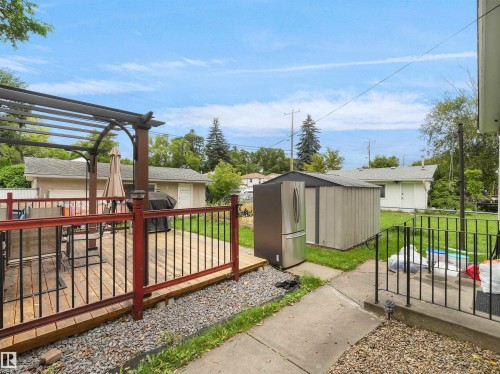 Expansive backyard featuring a wood deck with a pergola, metal railings, and a storage shed - 12002 48 Street Nw, Edmonton, AB 