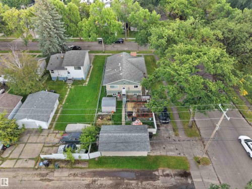 Property featuring a detached garage, established trees, and a concrete driveway - 12002 48 Street Nw, Edmonton, AB 