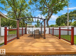 Expansive wood deck with a pergola, dark wood posts, and red-stained railings with black balusters - 