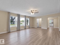 Expansive room featuring wood-finish flooring, multiple windows, a ceiling fan, and light-toned wall finishes - 