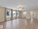 Expansive room featuring wood-finish flooring, multiple windows, a ceiling fan, and light-toned wall finishes - 12002 48 Street Nw, Edmonton, AB 