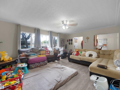 Wood-finish flooring throughout the room, featuring multiple windows with natural light and a ceiling fan with integrated lighting - 12002 48 Street Nw, Edmonton, AB 