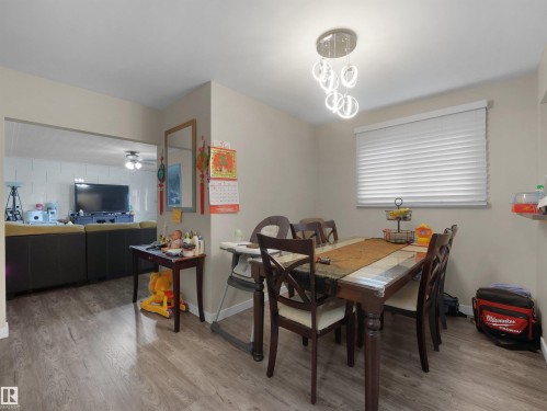 Wood-finish flooring throughout, a modern chandelier, and a wide window with blinds - 12002 48 Street Nw, Edmonton, AB 