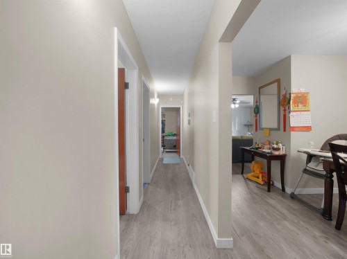 Hallway featuring wood-finish flooring, light neutral wall paint, and white trim - 12002 48 Street Nw, Edmonton, AB 