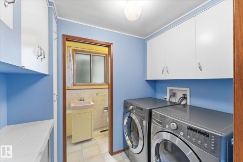 Laundry area featuring a ceiling-mounted light fixture, white upper cabinetry, and a countertop with white tile - 11311 Malmo Road Nw, Edmonton, AB 