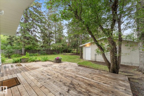 Expansive wood deck with a large manicured lawn, mature trees, and a detached building - 11311 Malmo Road Nw, Edmonton, AB 