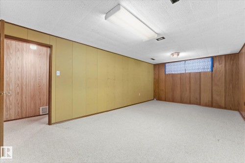 Expansive room featuring carpet flooring, panel walls, and a drop ceiling with recessed lighting - 11311 Malmo Road Nw, Edmonton, AB 