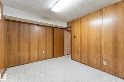 Wood-paneled walls and neutral carpeting with a flat white ceiling - 11311 Malmo Road Nw, Edmonton, AB 