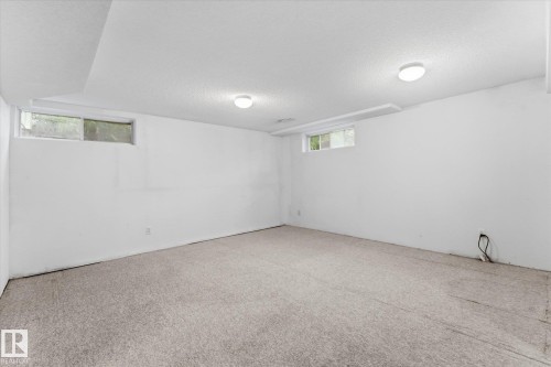 Recessed lighting illuminates a spacious room featuring wall-to-wall carpeting and two windows - 11311 Malmo Road Nw, Edmonton, AB 