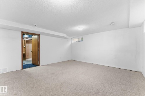 Spacious room with light-colored carpeting, white painted walls, and a dropped ceiling with recessed lighting - 11311 Malmo Road Nw, Edmonton, AB 