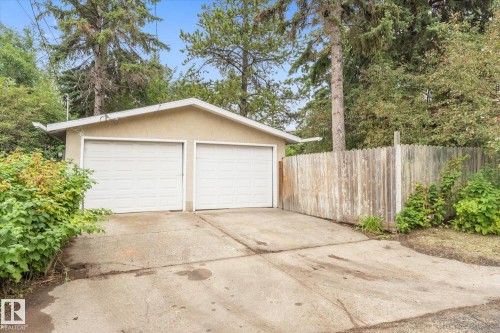 Detached garage with two white panel doors, stucco exterior, and a concrete driveway - 11311 Malmo Road Nw, Edmonton, AB 