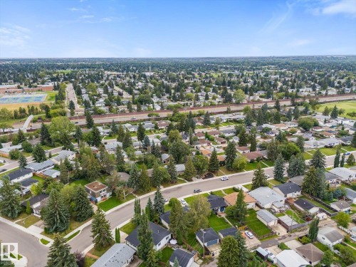 Expansive residential neighborhood with mature trees, paved streets, and a clear blue sky - 11311 Malmo Road Nw, Edmonton, AB 