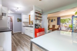 Modern kitchen featuring white cabinetry, dark countertops, wood-finish flooring, and recessed lighting - 