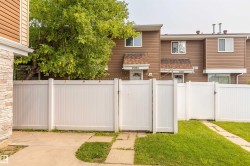 Private outdoor space featuring a white vinyl fence with gate, concrete patio, and grass area - 