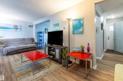Open-concept living area with wood-finish flooring, light-colored walls, and a recessed ceiling - 