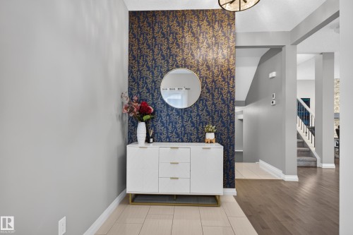 Foyer featuring patterned accent wall and light-toned tile flooring - 22933 94A Avenue Nw, Edmonton, AB 