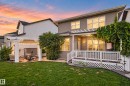 Expansive backyard featuring a manicured lawn, a white pergola-covered patio, and a raised wood-finish deck with white railings - 22933 94A Avenue Nw, Edmonton, AB 