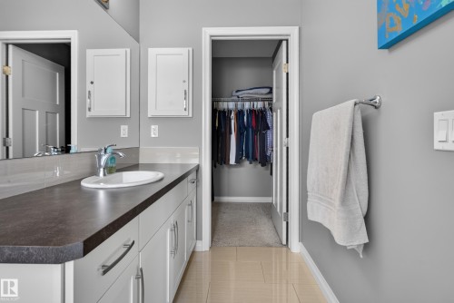 Vanity with an integrated sink, dark countertop, and white cabinetry featuring chrome hardware - 22933 94A Avenue Nw, Edmonton, AB 