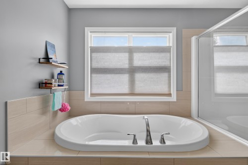 Built-in soaking tub with deck-mounted faucet, surrounded by tiled surfaces - 22933 94A Avenue Nw, Edmonton, AB 