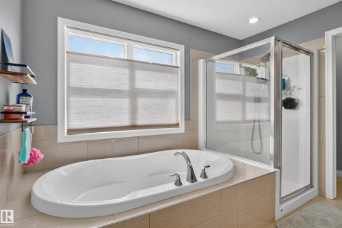 Integrated soaking tub with chrome fixtures, tiled tub surround, and separate glass-enclosed shower - 22933 94A Avenue Nw, Edmonton, AB 