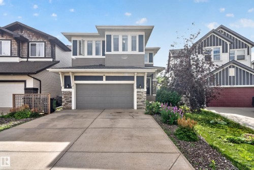 Contemporary exterior with a multi-level design, attached two-car garage, stone accents, and mature landscaping - 22933 94A Avenue Nw, Edmonton, AB 