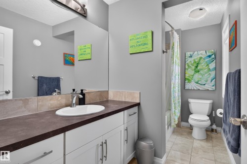 Bathroom featuring a single vanity with a dark countertop, white cabinetry, and a full-width mirror - 22933 94A Avenue Nw, Edmonton, AB 