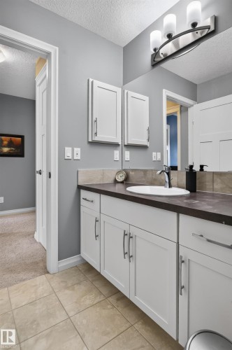 Vanity with white cabinetry, dark countertop, and integrated sink - 22933 94A Avenue Nw, Edmonton, AB 