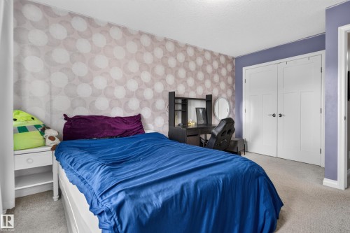 Recessed lighting, patterned accent wall, white paneled bifold doors, and carpet flooring - 22933 94A Avenue Nw, Edmonton, AB 