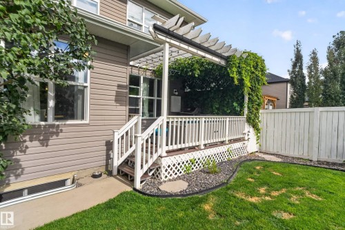 Exterior siding with multiple windows, leading to a raised deck with white railings and a pergola - 22933 94A Avenue Nw, Edmonton, AB 