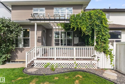 Rear exterior featuring a wood deck with white railings, a pergola, and a privacy fence - 22933 94A Avenue Nw, Edmonton, AB 