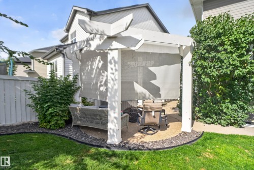 Outdoor pergola with privacy screens, pea gravel hardscaping, and surrounding green lawn - 22933 94A Avenue Nw, Edmonton, AB 