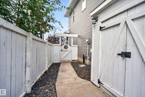 White privacy fence with a concrete pathway and decorative stone landscaping - 22933 94A Avenue Nw, Edmonton, AB 