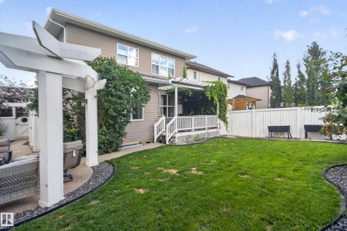 Expansive backyard featuring a manicured lawn, a white privacy fence, and a white pergola over a concrete patio - 22933 94A Avenue Nw, Edmonton, AB 