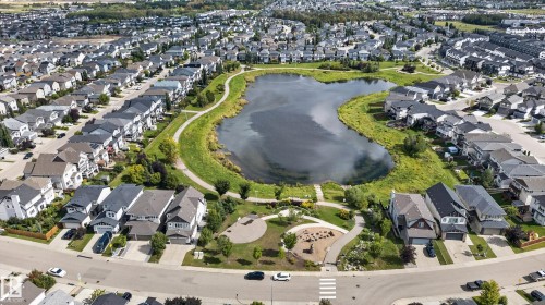 Aerial perspective highlighting a residential development with a central pond feature, surrounding green spaces, and a pedestrian pathway system - 22933 94A Avenue Nw, Edmonton, AB 