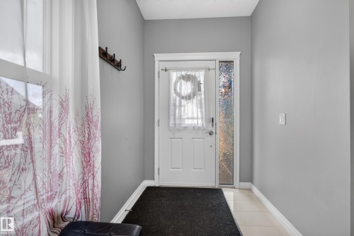 Entryway featuring a white door with a clear glass insert, an opaque sidelight, and light-toned tile flooring - 22933 94A Avenue Nw, Edmonton, AB 