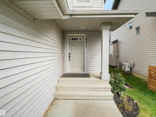 Entry with light-toned siding and a covered porch - 6656 Cardinal Rd Sw, Edmonton, AB 