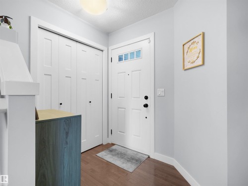 Entryway featuring a white paneled door with glass inserts, wood-finish flooring, and a flush mount ceiling light - 6656 Cardinal Rd Sw, Edmonton, AB 