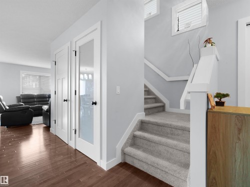 Wood-finish flooring, white trim, solid white doors, glass panel door, and carpeted staircase - 6656 Cardinal Rd Sw, Edmonton, AB 