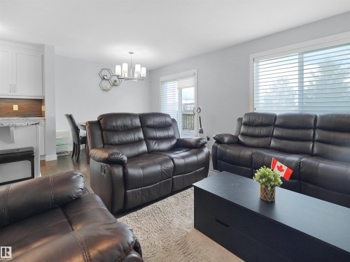 Hardwood-style flooring, white walls, modern chandelier, white cabinetry, and sliding glass door - 6656 Cardinal Rd Sw, Edmonton, AB 