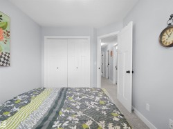 Textured gray carpeting, light blue wall paint, white interior doors, and white bi-fold closet doors - 
