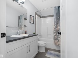 Bathroom featuring a white vanity with slab-panel doors, a dark countertop, an undermount sink, and a chrome faucet - 