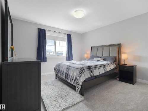Neutral wall paint with textured carpeting, and a window featuring white trim and dark draperies - 6656 Cardinal Rd Sw, Edmonton, AB 