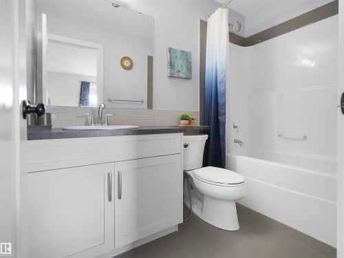 Vanity with a rectangular undermount sink, gray countertop, and brushed nickel faucet - 6656 Cardinal Rd Sw, Edmonton, AB 