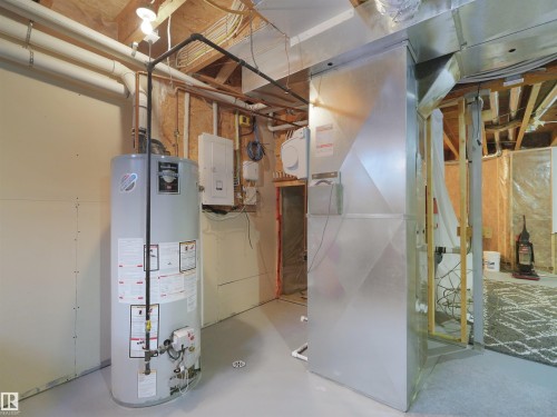Utility area featuring a water heater, furnace, and exposed ceiling joists - 6656 Cardinal Rd Sw, Edmonton, AB 