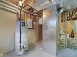 Utility area featuring a water heater, furnace, and exposed ceiling joists - 